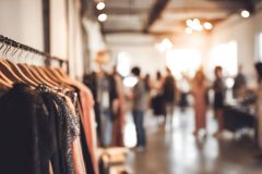 Medium closeup of a stylish popup shop interior in an urban setting highlighting unique merchandise sharply framed against blurred customers and decor.